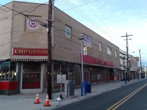 A street view of a brick building with storefronts and awnings.