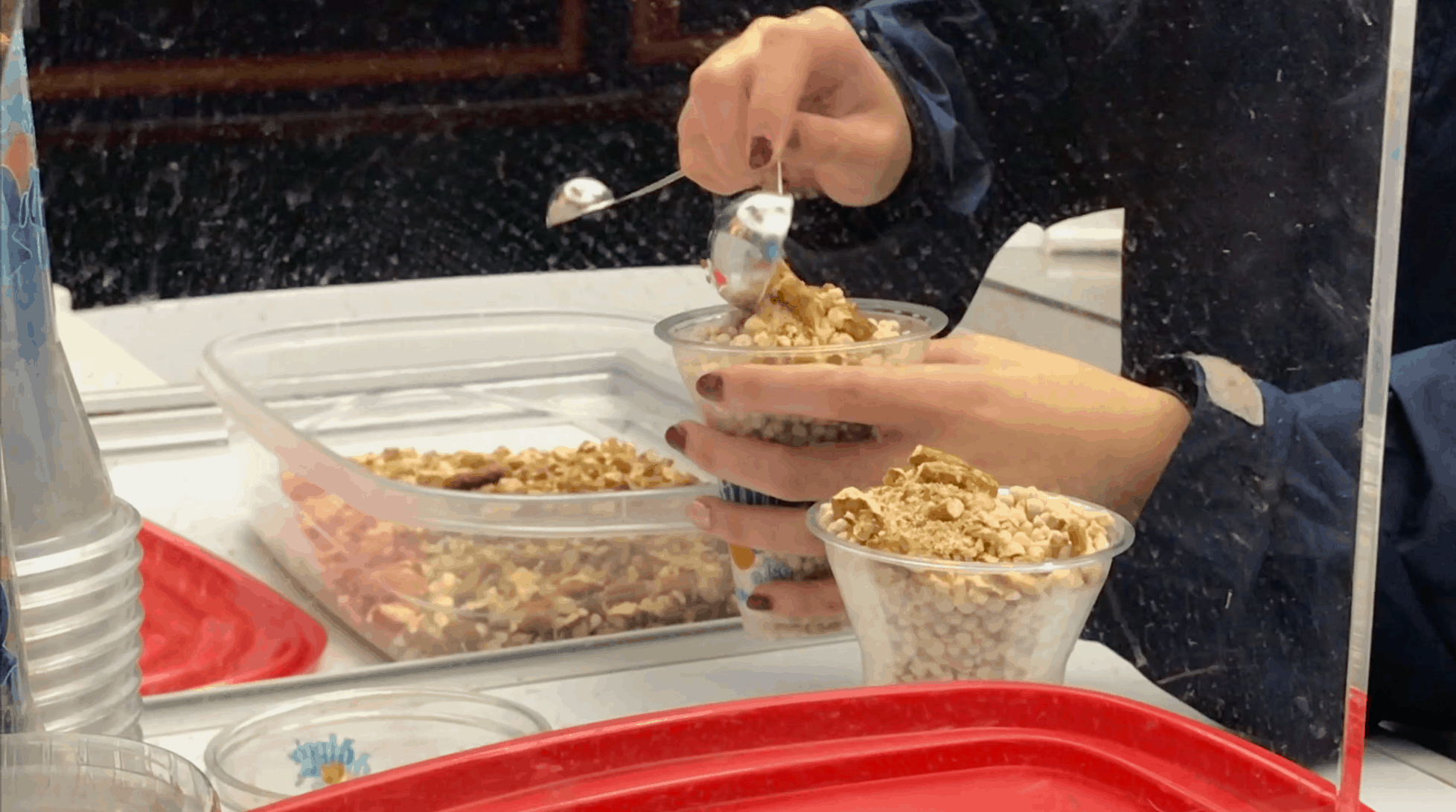 A child scooping cereal into a cup.