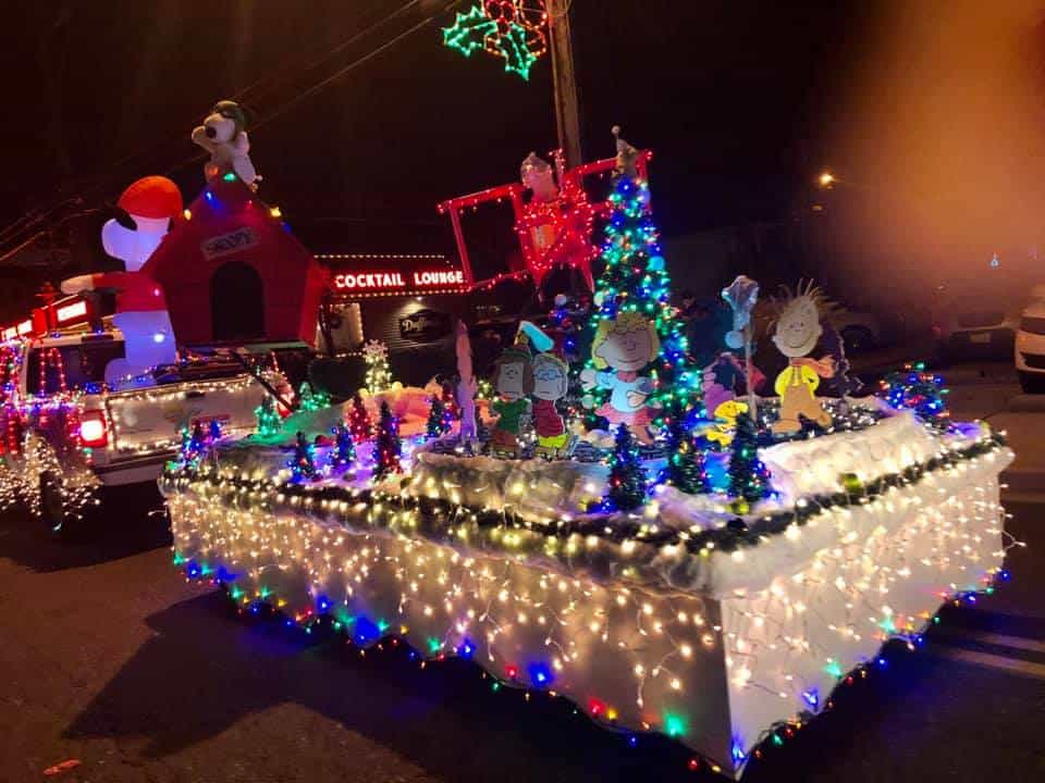 A festive parade float decorated with Christmas lights and holiday figures.