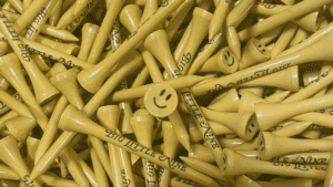 A pile of yellow golf tees with smiley faces and text.
