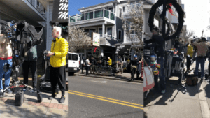 A man in a yellow jacket walking on a sidewalk in an urban area.