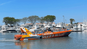 A colorful boat named Silver Bullet docked by the shore on a sunny day.