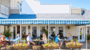 People dining outdoors under a blue and white striped awning at a cafe.