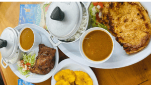 A meal with rice, beans, fried chicken, and plantains on white plates.