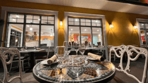Cozy outdoor dining table set for two with wine glasses and candles at night.