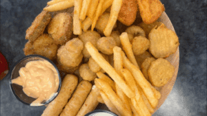 A close-up of fried fast food items including fries, chicken nuggets, and mozzarella sticks.