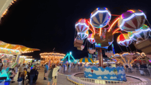 People enjoying a brightly lit carnival ride at night.