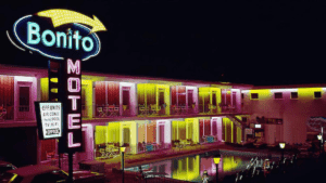 A neon-lit motel at night with colorful lights reflecting in the pool.