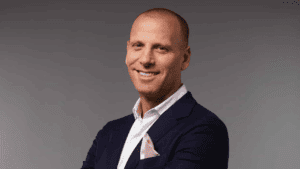 A professional man in a dark suit smiling at the camera.