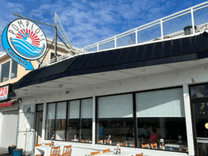 Exterior of a modern restaurant with outdoor seating under a blue sky.
