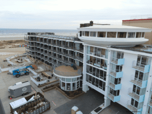 A modern multi-story hotel building near the coast under a cloudy sky.