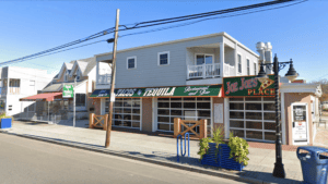 A two-story building with multiple storefronts on a sunny street.