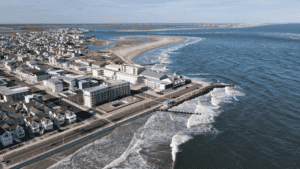 A coastal town with buildings near the beach and waves crashing on the shore.