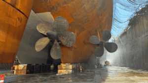 Two large ship propellers under a vessel's hull.