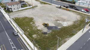 A construction vehicle working on a gravel lot near a road.