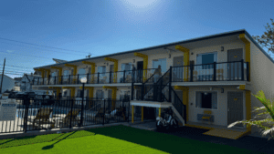 Two-story motel with exterior corridors and balconies under a clear blue sky.