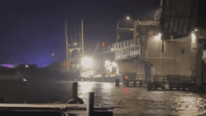A boat dock at night with bright lights and a person working on the pier.