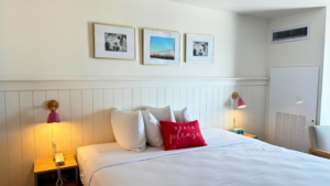 Cozy bedroom with white bedding and decorative pillows including a red one saying 'our happy place'.