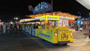 Brightly lit Sightseer tour tram at night packed with passengers.