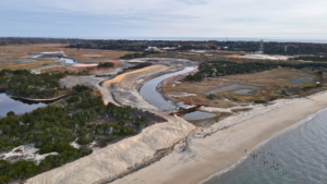 A river meandering through a sandy construction site near the coast.