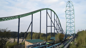 A large green roller coaster with a curved drop and a blue sky.