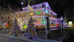 A house decorated with colorful Christmas lights and two lit Christmas trees.