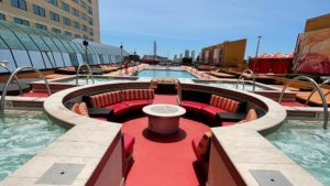 Modern outdoor pool area with red circular seating and a cityscape view.