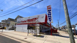 A market sign being painted on a building under a clear blue sky.