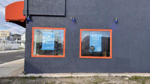 Two windows with blue posters on a dark wall.
