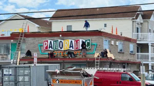 Workers renovate the Panoramic Hotel sign on a rooftop.
