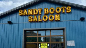 The sign of Sandy Boots Saloon in gold letters on a blue building.