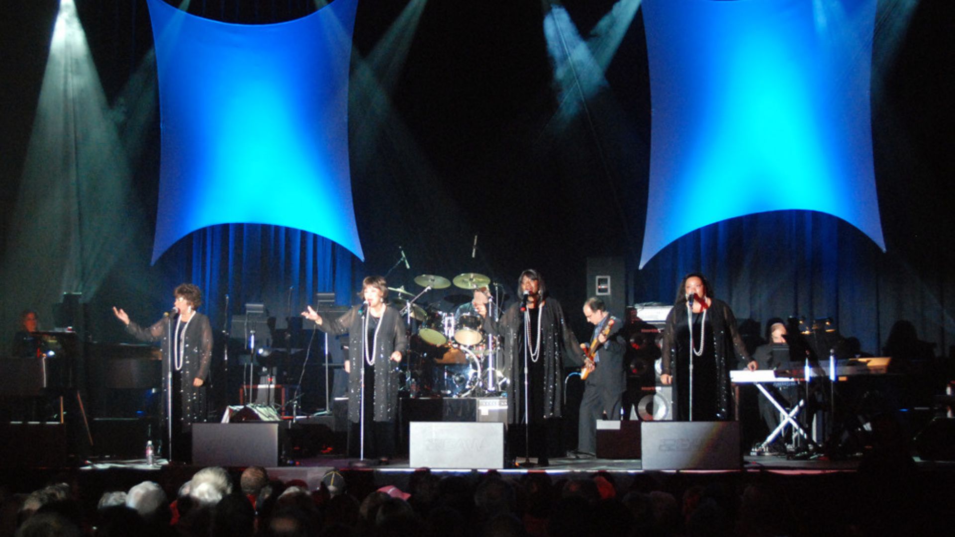 Musical group performing on stage with lights.