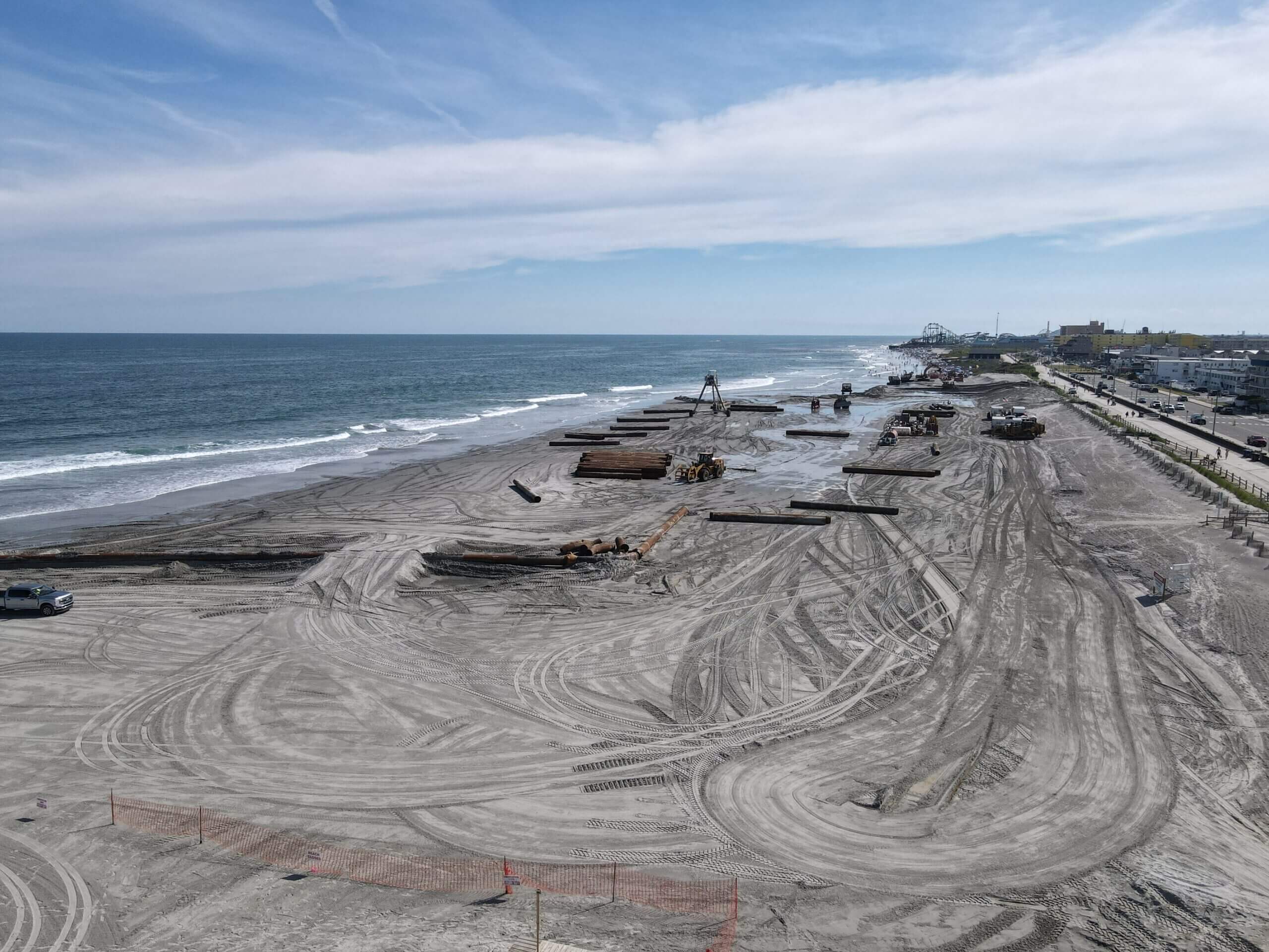 Beach construction site with heavy machinery and ocean.