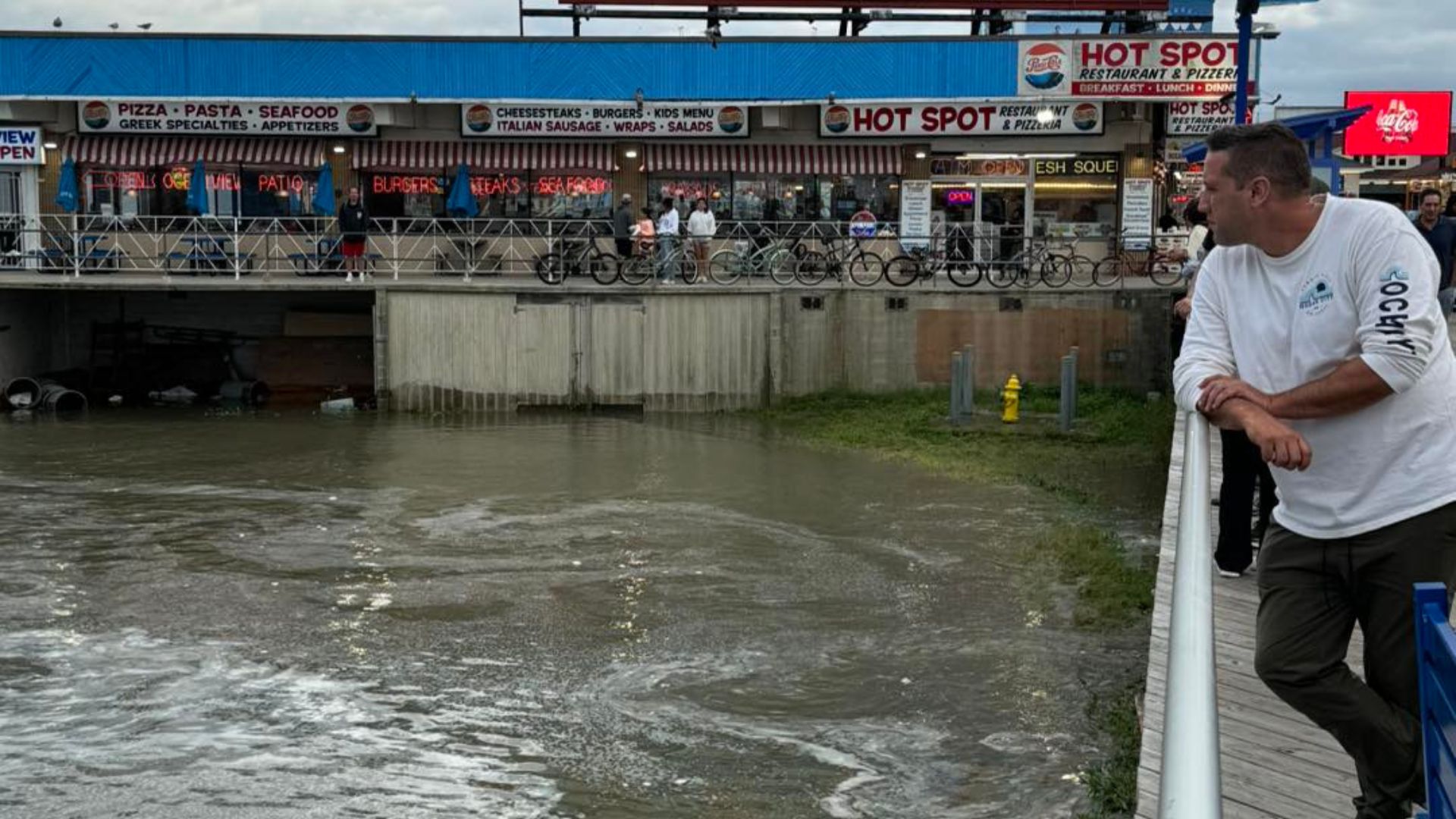 Man observing flooded area near restaurants.